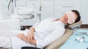 Paciente relaxando com máscara de dormir na cadeira odontológica, ilustrando a conexão entre odontologia e saúde do sono