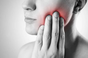 Dentista avaliando dente do siso inflamado em consulta
